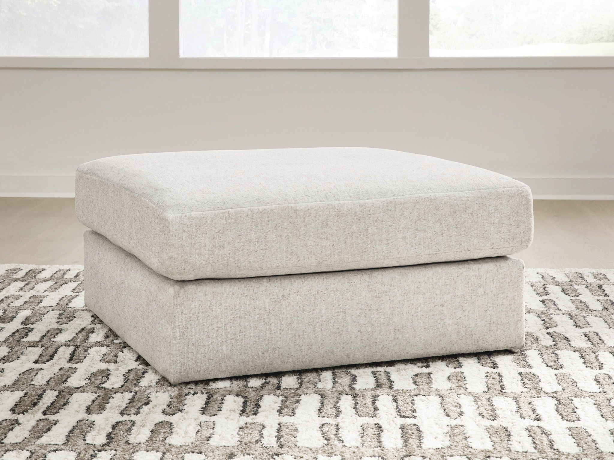 Light beige upholstered accent ottoman with rounded top and cushioned base