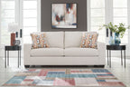 Light gray sofa with two patterned throw pillows and rolled arms