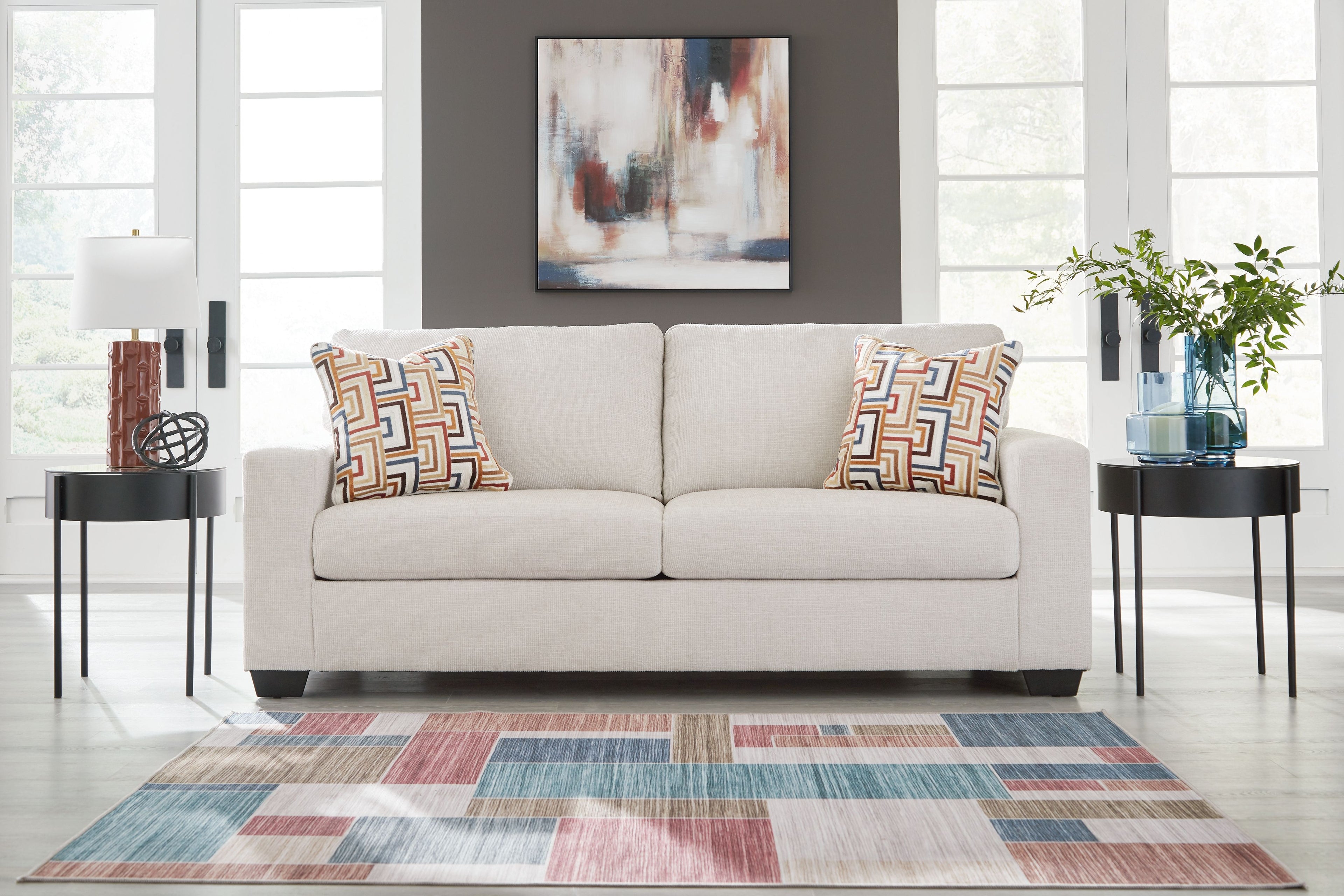 Light gray sofa with two patterned throw pillows and rolled arms