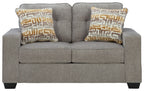 Gray upholstered loveseat with two square geometric-pattern throw pillows
