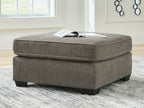 Dark gray upholstered ottoman with tufted top and squared black legs