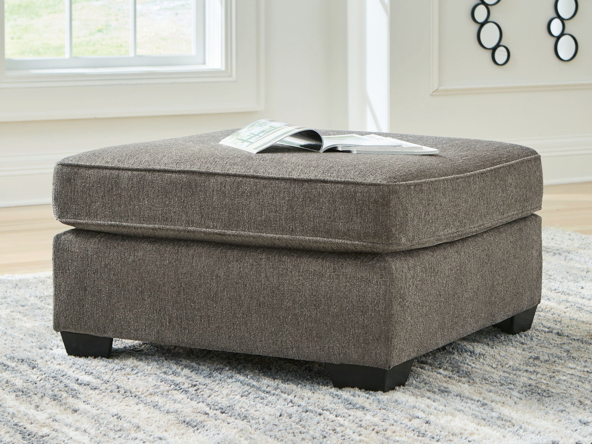 Dark gray upholstered ottoman with tufted top and squared black legs