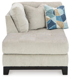 Stone corner chaise section with rounded arm, plush cushions, geometric patterned throw pillow