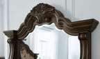 Dark brown arched mirror frame with carved scrollwork and crest detail