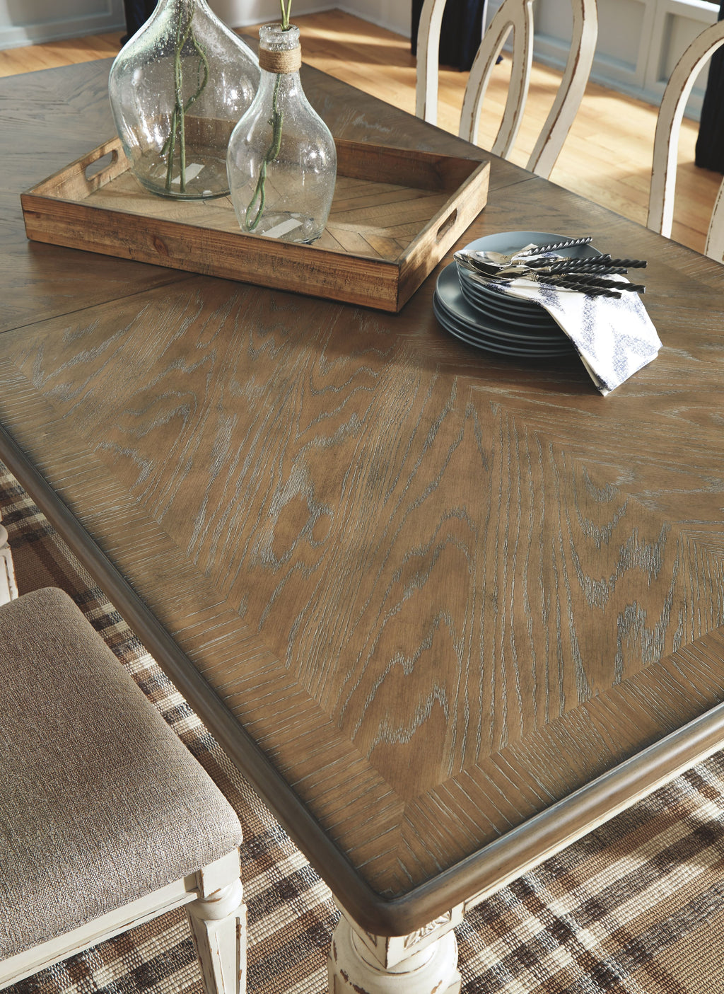Wood dining table corner with tabletop tray and stacked plates on surface