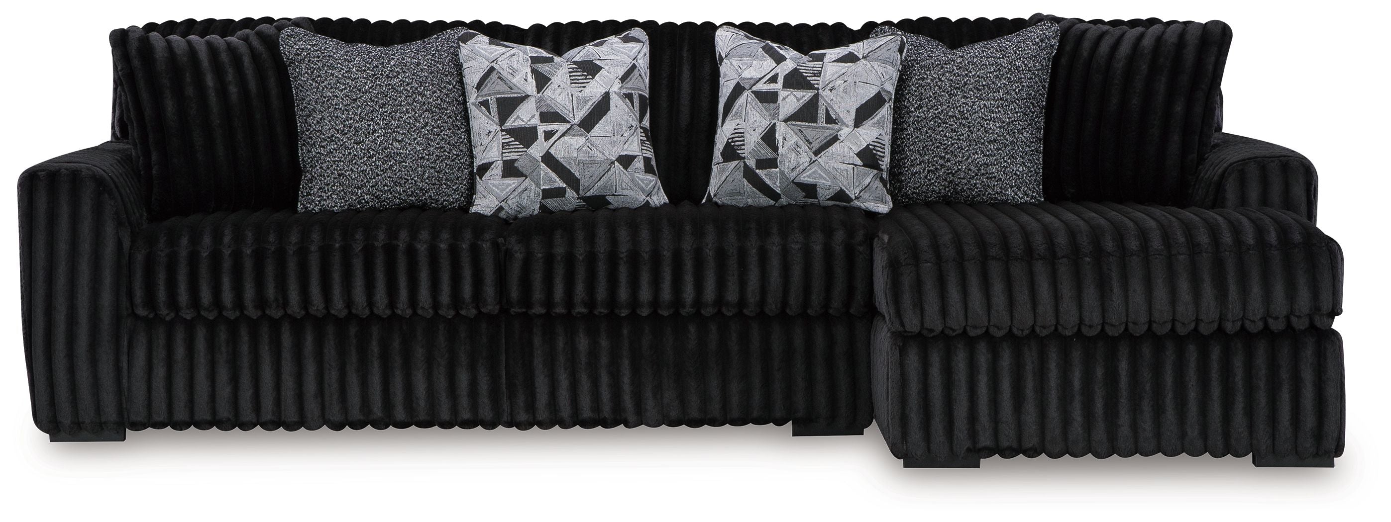 Black sectional sofa with chaise, ribbed upholstery, and two patterned throw pillows