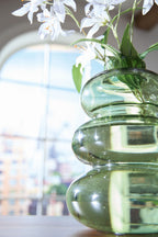 Green glass stacked vase close-up with glossy curved sections and neck opening.