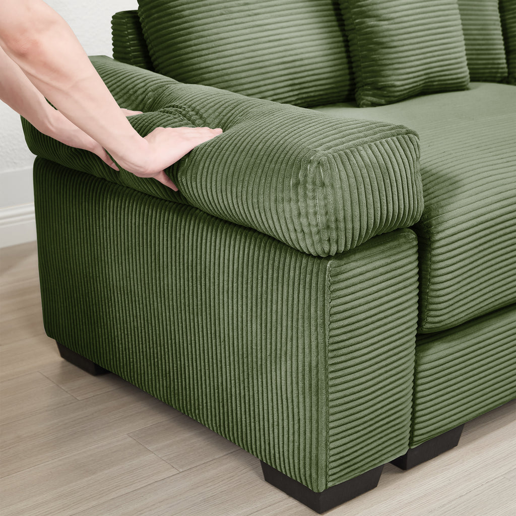Green corduroy sectional chaise with rounded ottoman seat being adjusted by hand