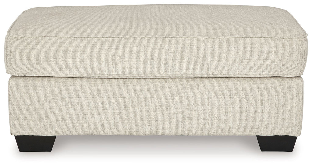 Light beige upholstered ottoman front view with dark legs