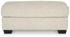 Light beige upholstered ottoman front view with dark legs