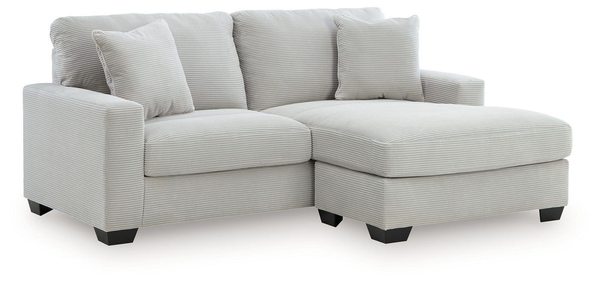Gray upholstered sofa with chaise extension and tufted back cushions