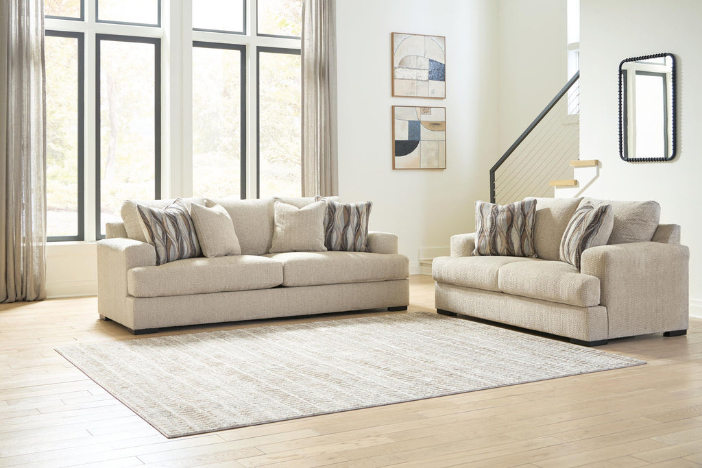 Oatmeal fabric sofa and loveseat set with striped pillows on area rug