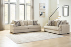Oatmeal fabric sofa and loveseat set with striped pillows on area rug