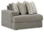 Gray upholstered corner chair with three decorative pillows and wide cushioned seat