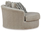 Light beige swivel accent chair with plush rounded arms and patterned back pillow