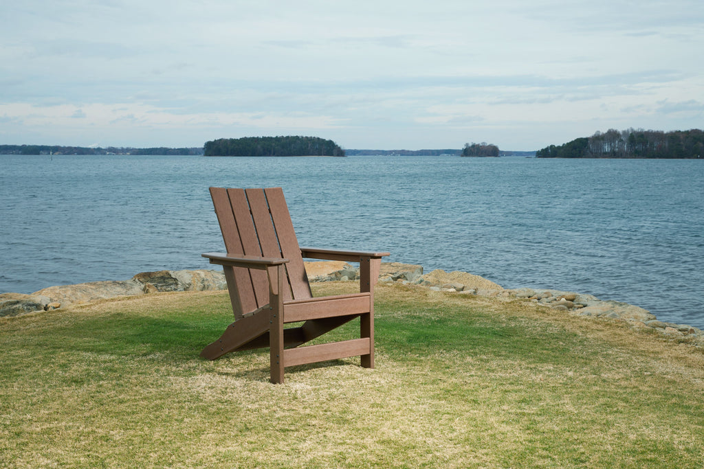 Brown Adirondack chair with slatted back and armrests.