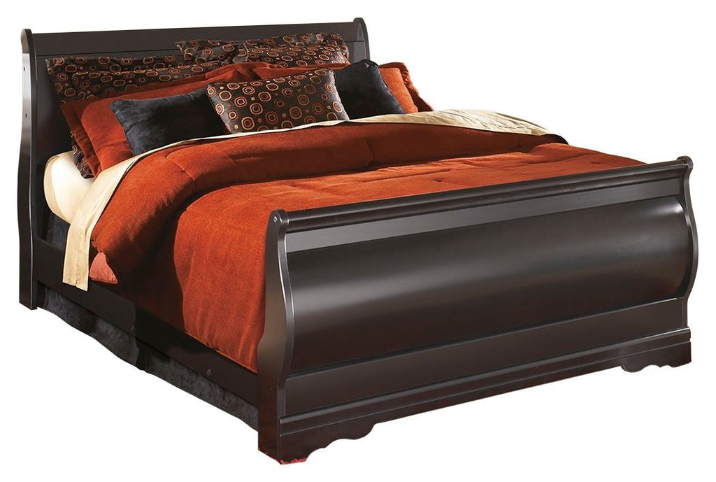 Black sleigh bed with curved headboard and footboard, orange quilt and patterned pillows