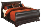 Black sleigh bed with curved headboard and footboard, orange quilt and patterned pillows