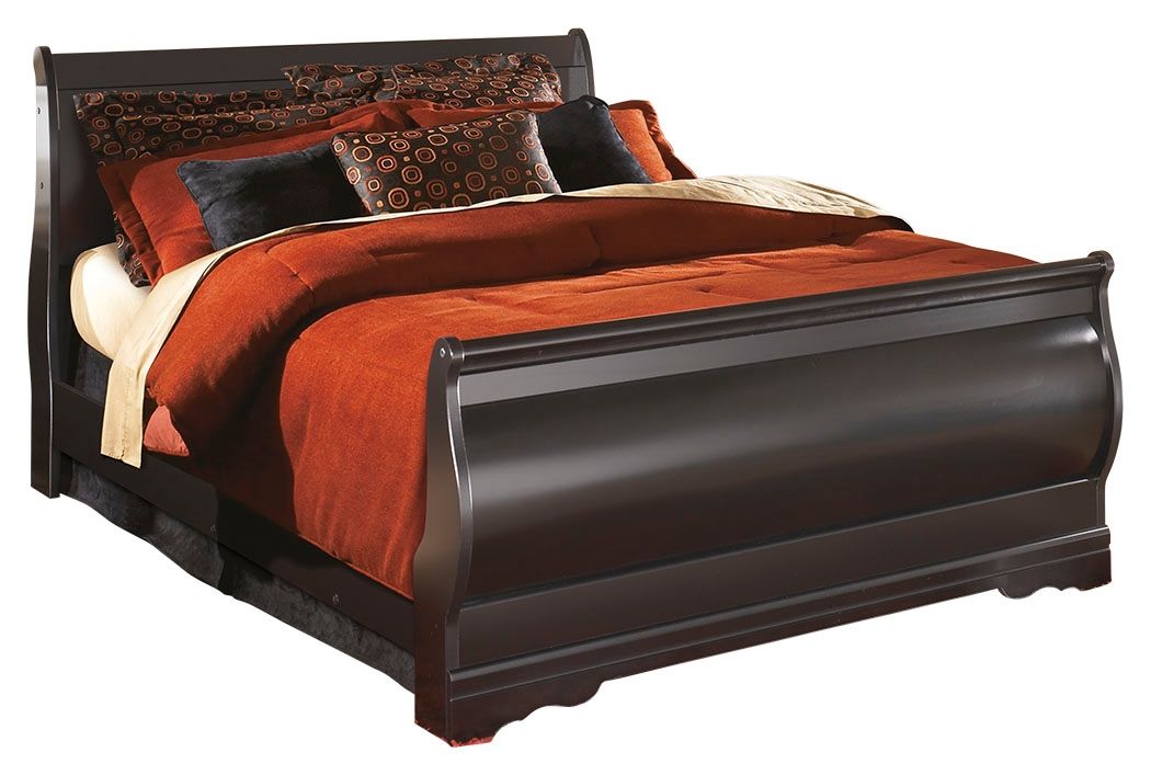 Black sleigh bed with curved headboard and footboard, orange quilt and patterned pillows