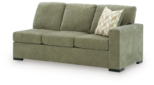 Moss green upholstered sofa with three back cushions and patterned accent pillow