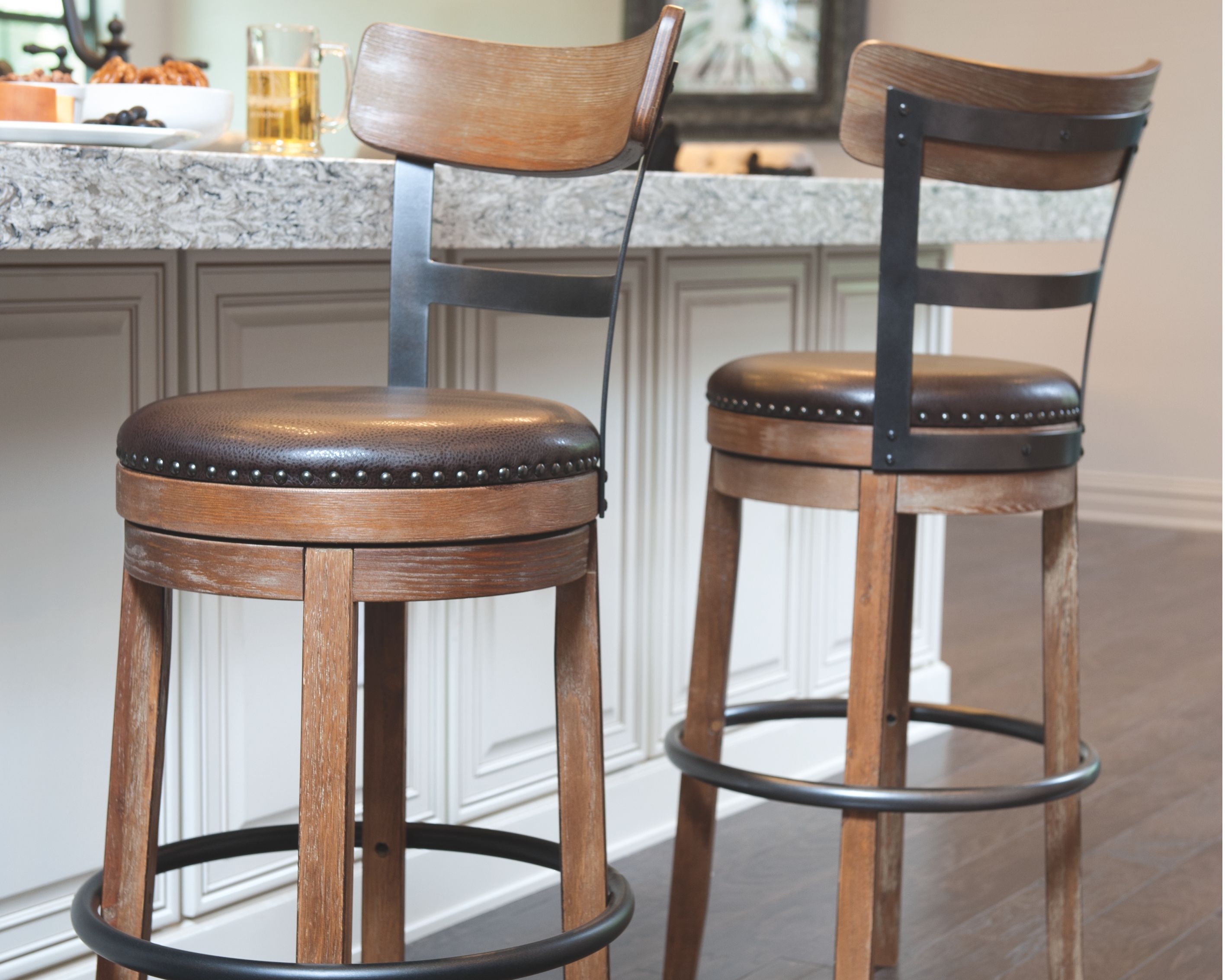 Two swivel barstools with dark round upholstered seats, light wood frames, and black swivel rings