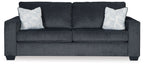 Slate stationary sofa with square arms, tufted back, and two light patterned throw pillows