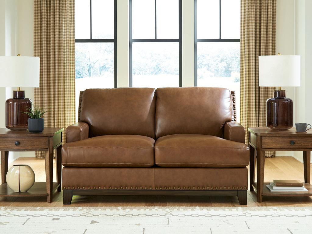 Brown loveseat sofa with padded back, two seat cushions, and nailhead trim along base