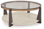 Round cocktail table with glass top, lower shelf, and dark wood legs with bronze rim