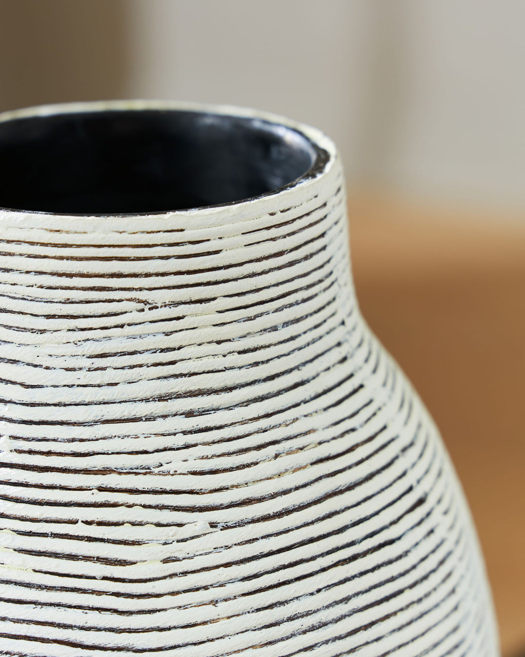 Close-up of vase neck opening with white striped texture on black ceramic