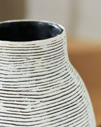 Close-up of vase neck opening with white striped texture on black ceramic