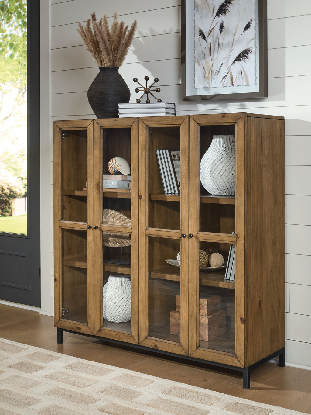 Gray-brown wooden accent cabinet with four doors, curved metal knobs, and shelves