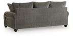 Gray upholstered sofa side profile with tufted armrests and dark legs