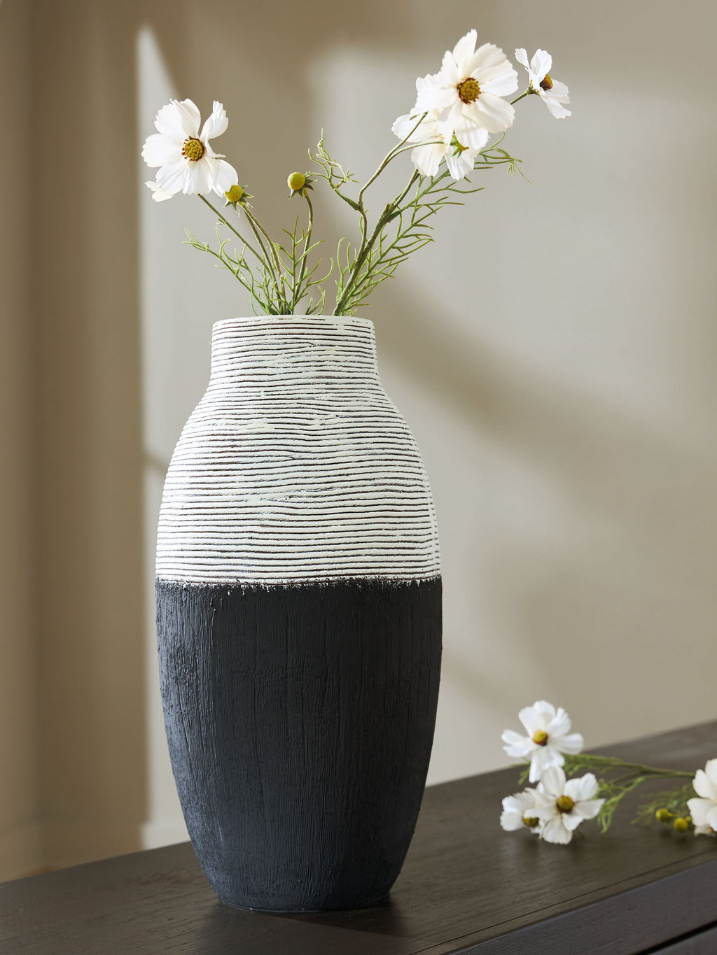 Black and white ceramic vase with white wildflower arrangement on tabletop