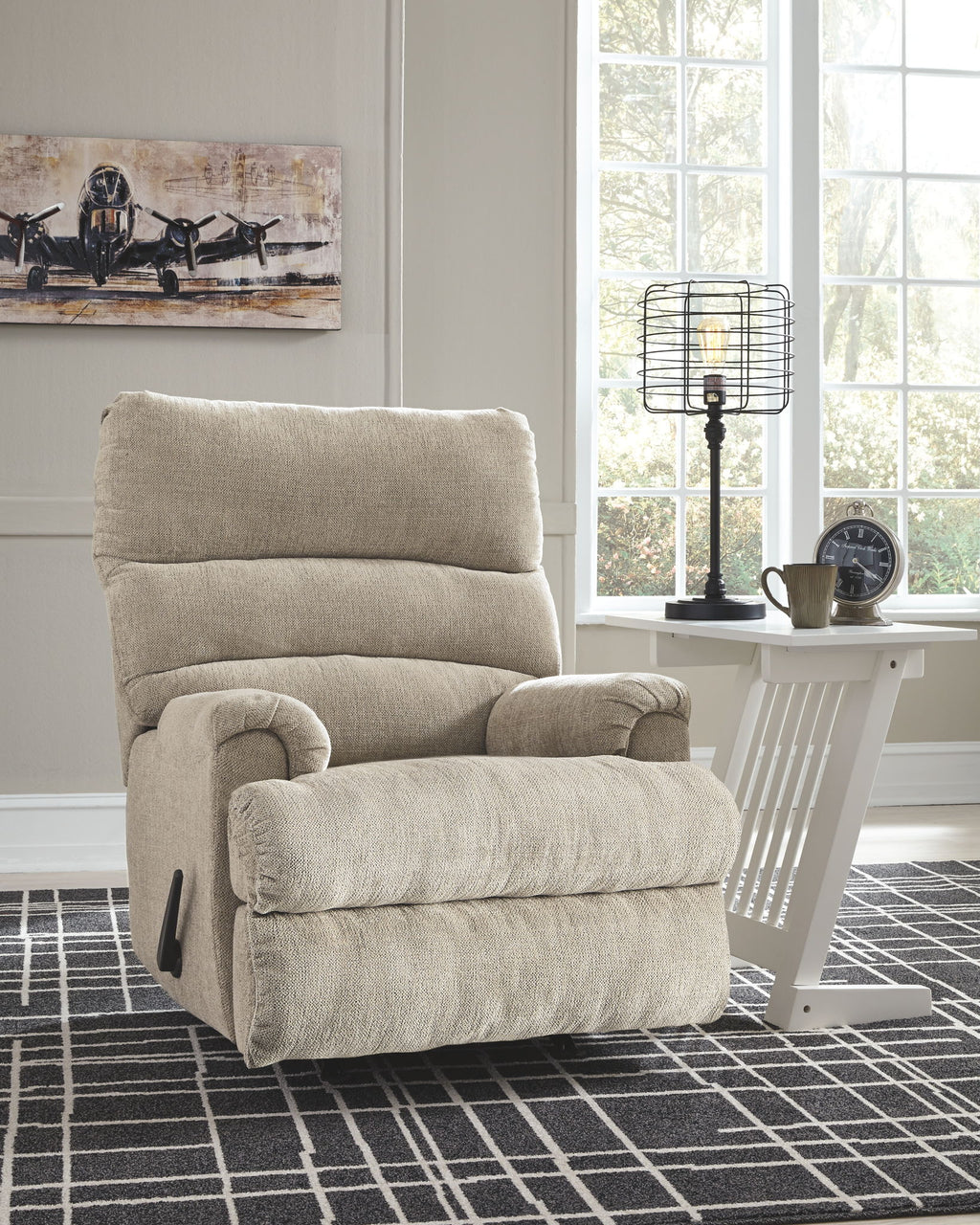 Rocking recliner chair with tall back cushion and padded arms in light fabric