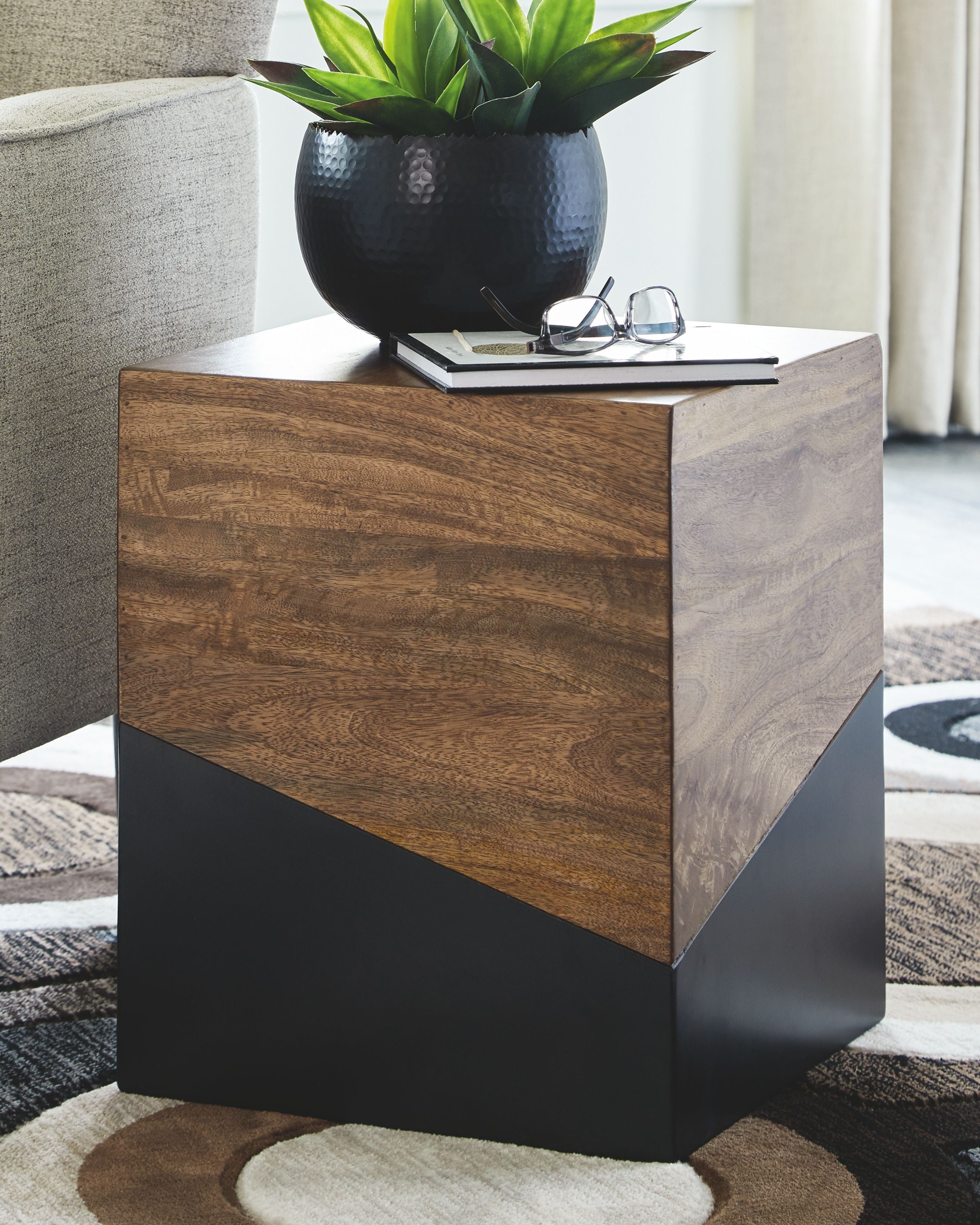 Brown wood accent table with gunmetal gray base with a small plant on top