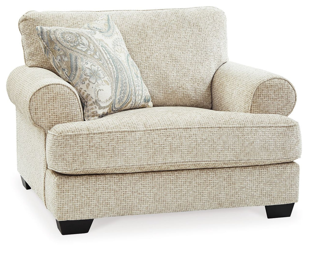 Sandstone chair and a half with rolled arms, light textured upholstery, and patterned throw pillow