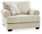 Sandstone chair and a half with rolled arms, light textured upholstery, and patterned throw pillow