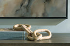 Light brown chain link sculpture with interlocked rings on a tabletop