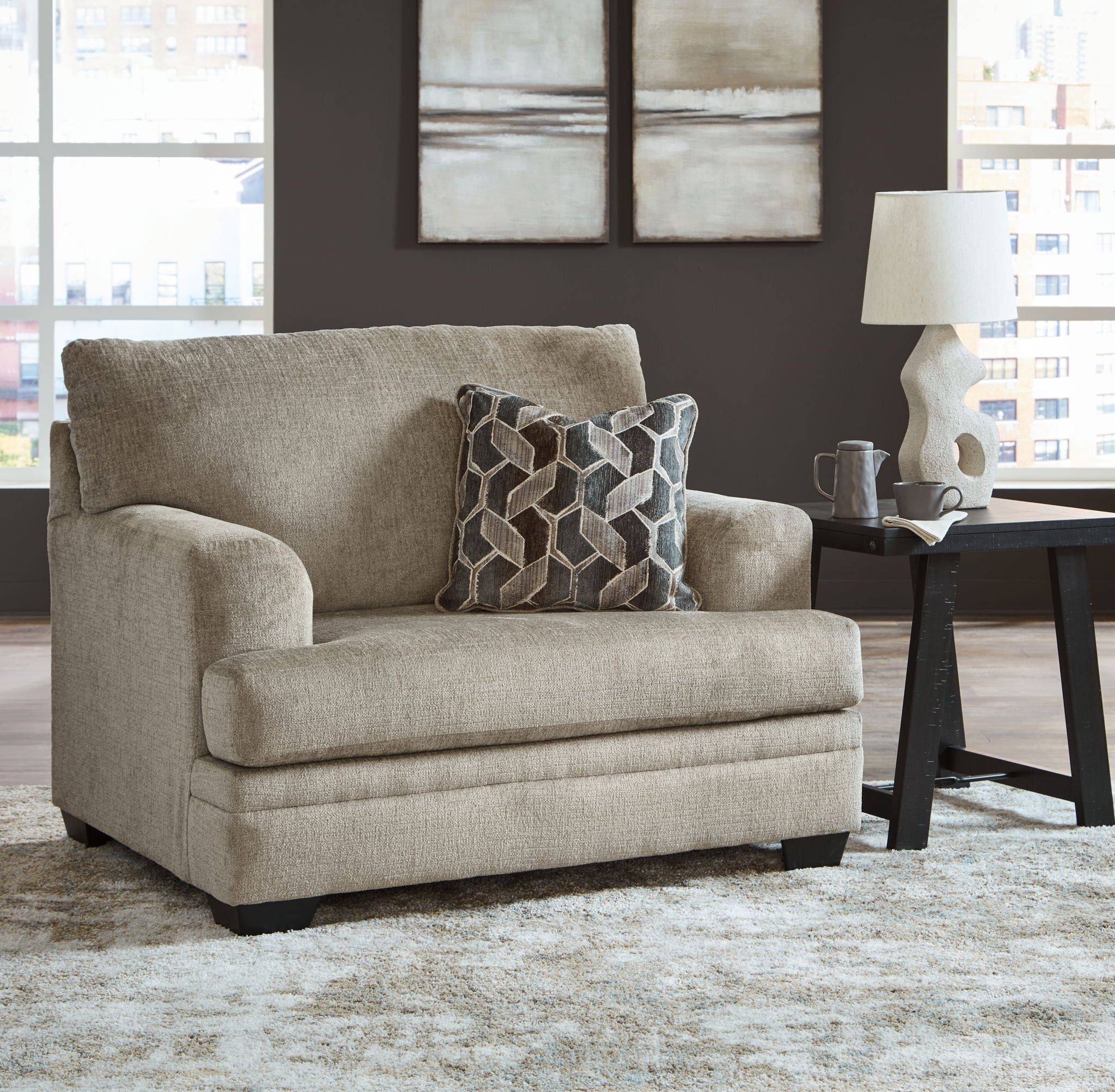 Light brown fabric accent chair with square arms and patterned throw pillow