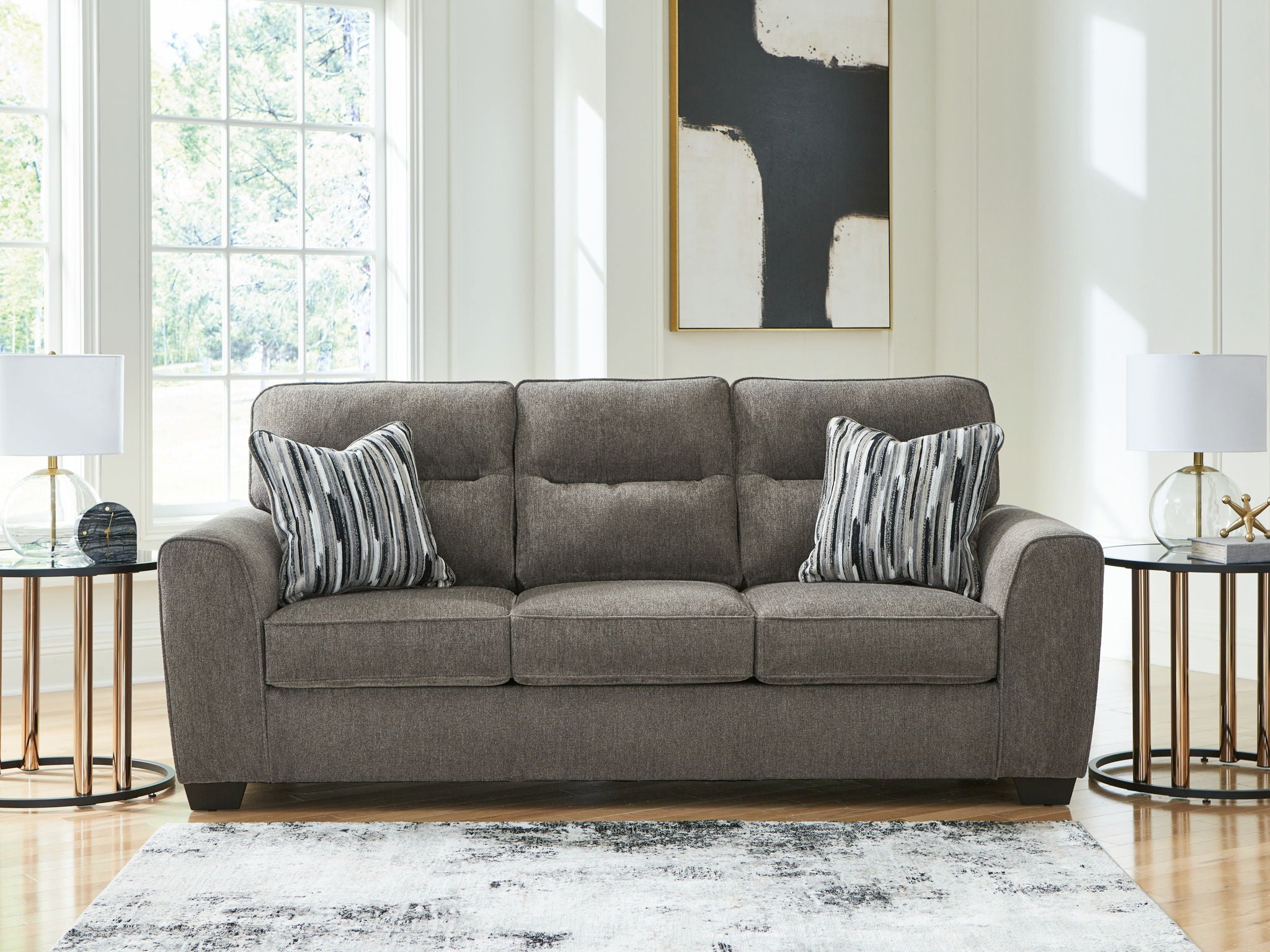 Dark gray fabric sofa with two striped pillows, front view