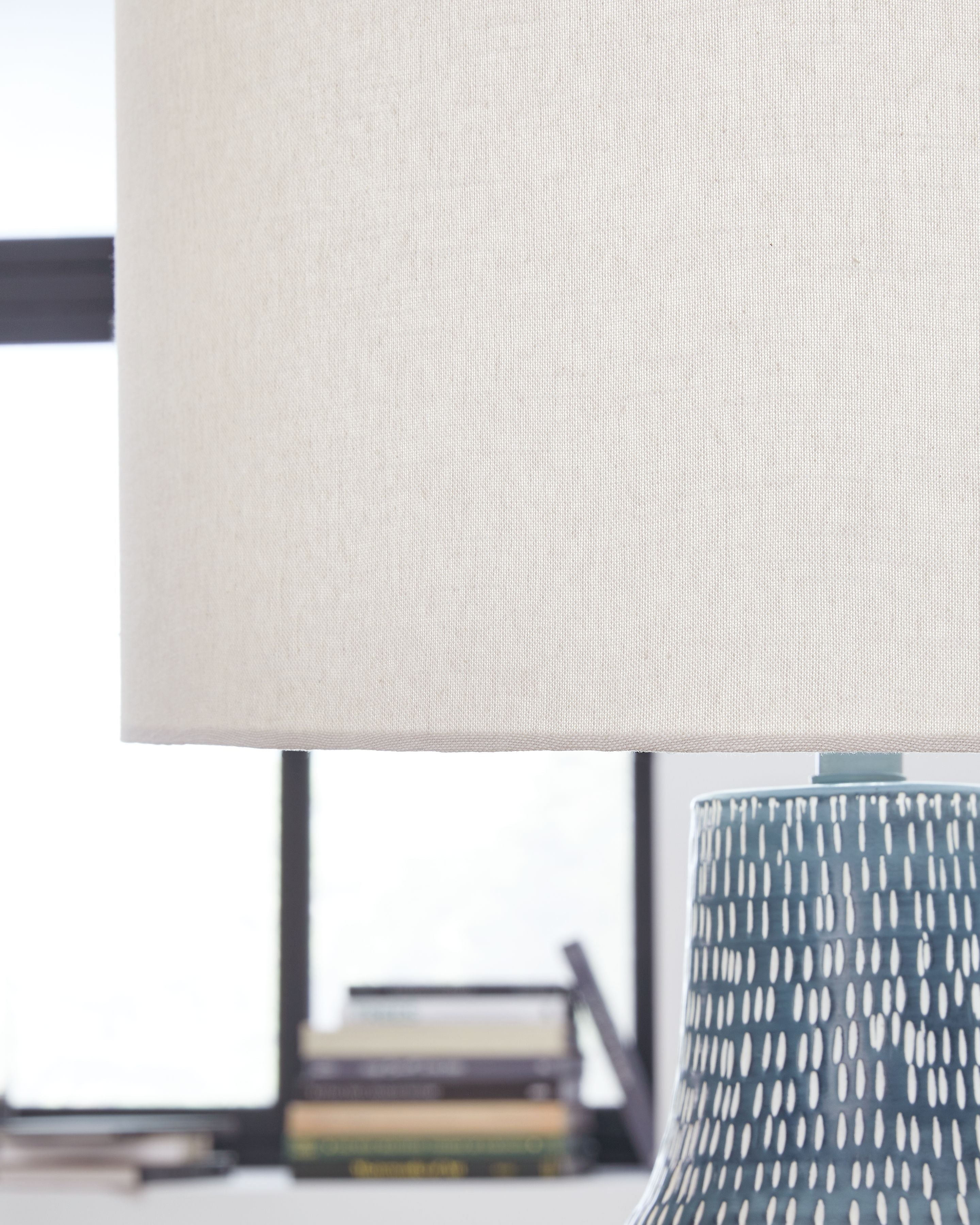 Table lamp with beige fabric drum shade and patterned metal base top
