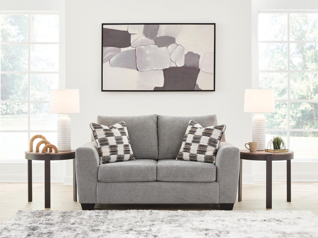 Gray upholstered loveseat with two checkered throw pillows and black legs