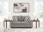 Gray upholstered loveseat with two checkered throw pillows and black legs