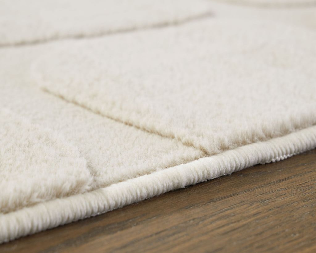 Washable beige rug close-up with thick plush pile and stitched edge