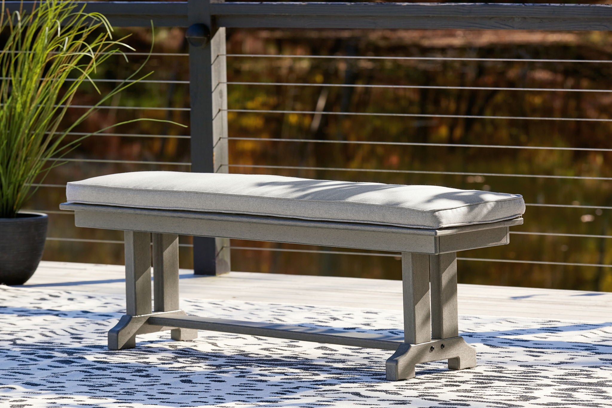 Gray outdoor bench with cushioned seat and backless bench frame, short thick legs