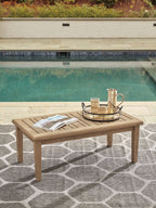 Rectangular cocktail table with beige wood top and tapered legs on outdoor patio.