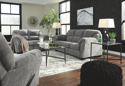 Dark gray sofa and loveseat set with matching pillows, rolled arms, and studded trim