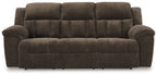 Chocolate brown reclining sofa with tufted seat and back, padded arms, and angled cushions