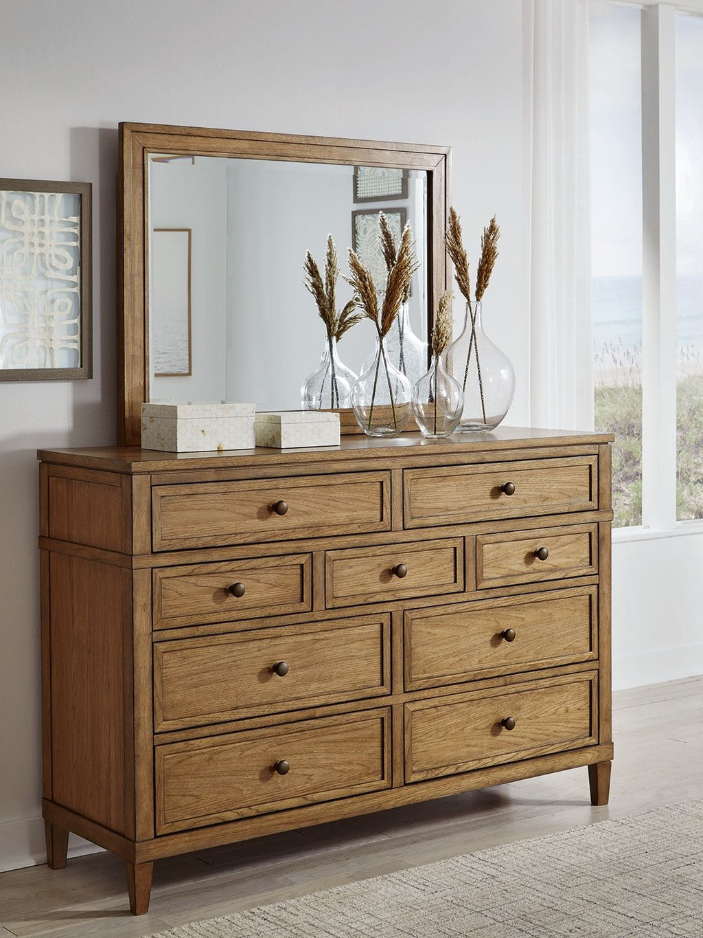 Light brown wood dresser with mirror and drawer fronts with round knobs