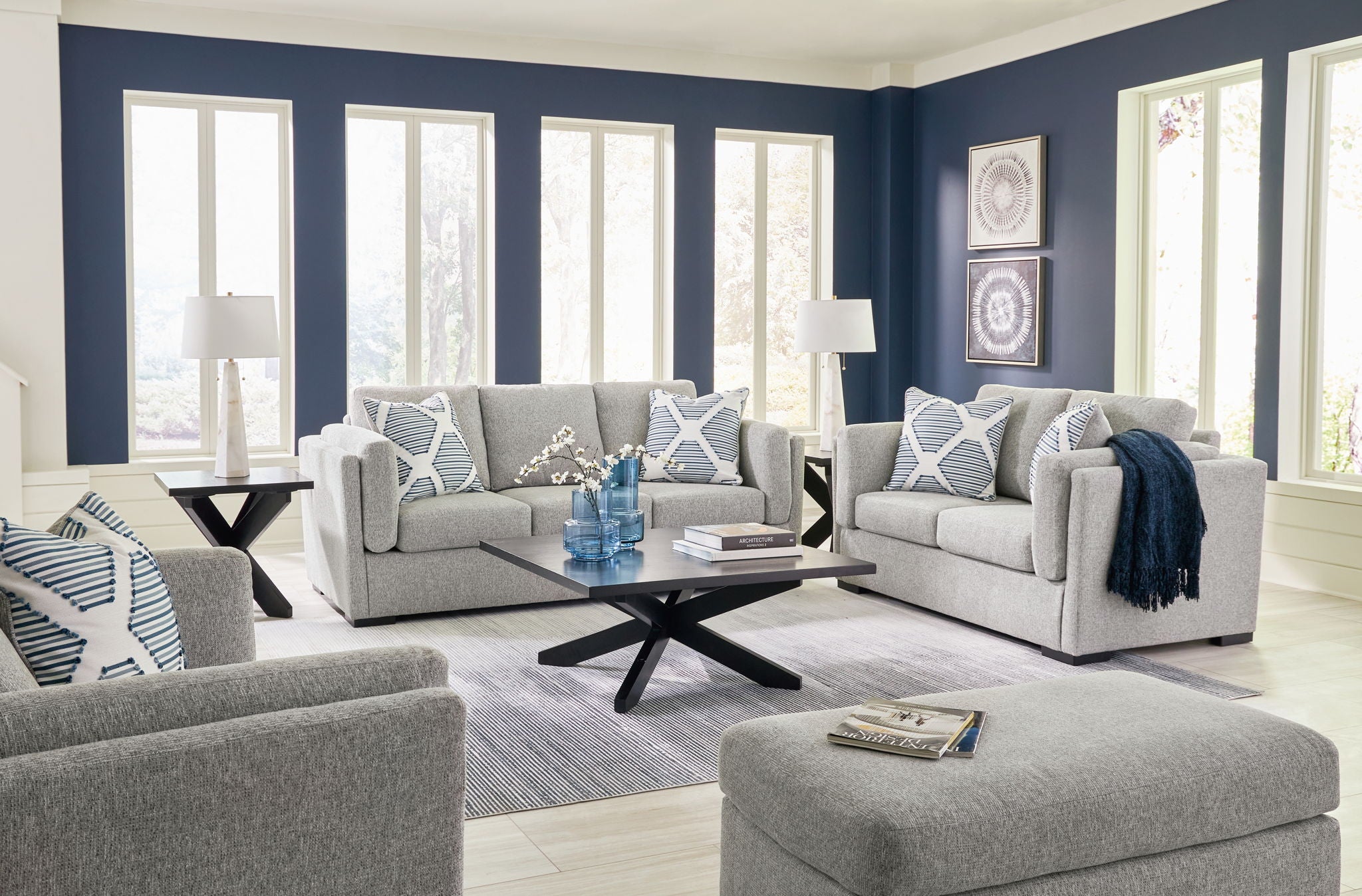 Gray living room sofa set with armchairs, patterned pillows, and a round ottoman